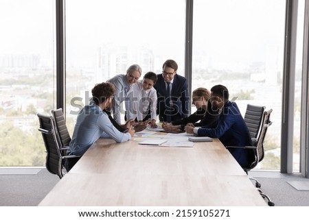 Older and young teammates gathered in modern office boardroom at corporate briefing, share solutions and creative ideas, discuss collaborative project feel satisfied. Teamwork, seminar event concept Foto stock © 
