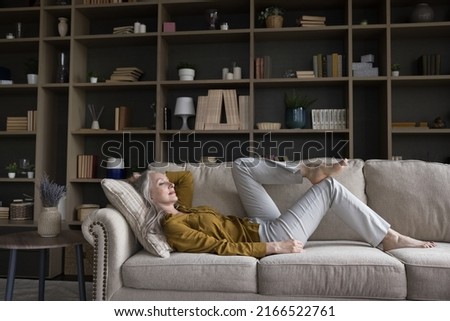 Middle-aged woman relaxing on cozy sofa in fashionable living room looking carefree enjoy repose at modern home, breath fresh conditioned air inside cozy flat. Free time, daydreaming, tenant concept Photo stock © 