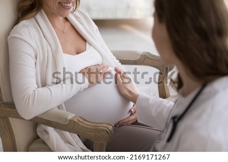 Hand of unknown obstetrician touches big belly of pregnant woman during visit at home, close up cropped shot. Prenatal care, doula consults future mother, pregnancy, motherhood and medicine concept Stockfoto © 