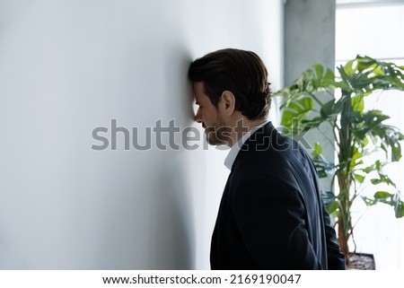 Upset businessman banging his head against wall in despair looks stressed having problems at work, bankruptcy, business failure unsuccessful negotiations, project loss, failed job interview concept Foto stock © 