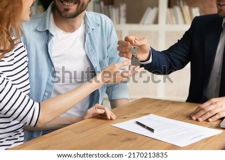 Cropped close up view happy couple receiving keys from new own property, finish meeting in real estate agency lead by realtor in formal suit. Bank mortgage for young family, selling, renting concept Foto stock © 