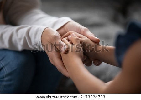 Close up compassionate young foster parent holding hands of little kid girl, giving psychological help, supporting at home. Sincere different generations family sharing secrets or making peace. Foto d'archivio © 