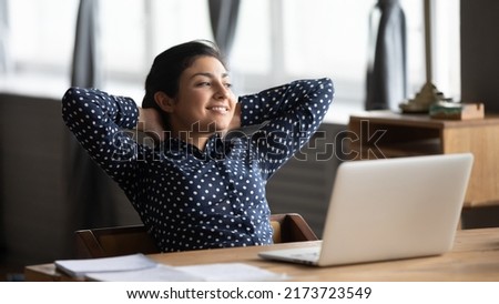 Carefree indian employee resting after productive workday leaned on office chair puts hands behind head look out the window feels well by career advance and achievement, dreams about vacation concept 商業照片 © 