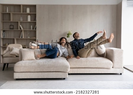 Foto Bild Junges lustiges Paar liegt mit Kissen, alten Büchern und Kopfhörern auf dem Boden im Sonnenscheinschatten