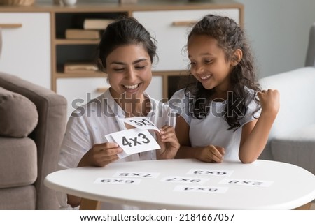 Happy Indian daycare teacher showing flash cards to little kid, helping child with multiplication table study, giving math lesson, talking, smiling, laughing. Mom teaching girl to count Foto stock © 