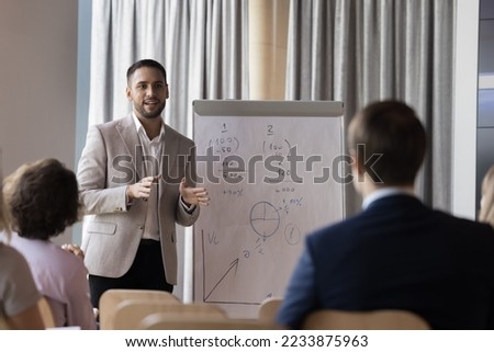 Man coach speaker in formal suit gives flip chart presentation, consulting group of client gathered in office, mentor leader explain graph strategy at team meeting, take part in business seminar event 商業照片 © 