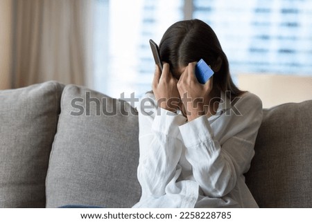 Desperate frustrated bank client woman facing scam, overspending, problems with online payments, blocked credit card, bankruptcy, holding smartphone, touching head, covering face Foto stock © 