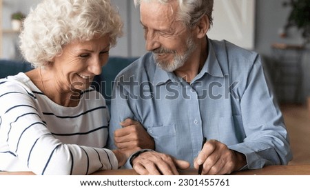 Happy senior older married couple discussing investing saving before signing paper agreement. Smiling middle aged man woman putting signature on marriage contract or making testate at lawyer office. Imagine de stoc © 