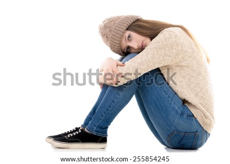 Sad teenage girl with problems sitting with her head on her knees, copy space