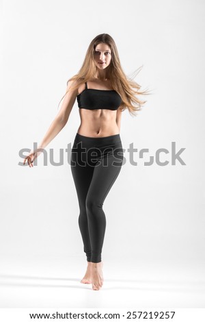 Sporty teenage girl dancing with long flowing hair, doing dynamic, energetic fitness practice with choreographic elements, in motion