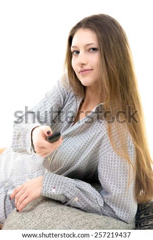Beautiful young girl lying comfortable, pressing button on remote control, switching channels on tv, watching television