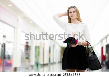 Confused young woman out of money holding opened wallet in mall, deciding on shopping, economy, tight budget, broke, copyspace