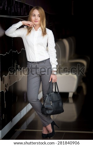 Full length portrait of office employee, attractive confident young business woman in white shirt with pensive expression
