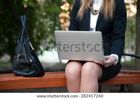 Young girl in trendy outfit using laptop, study, working, communicating, ordering online, sitting on the bench in city park, close-up