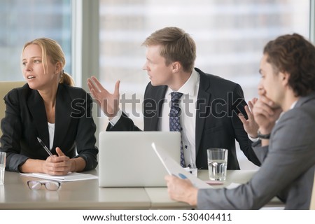 Furious boss scolding young frustrated interns with bad work results. Ineffective office workers sitting at the table and listening to irritated boss yelling with bored and annoyed expressions Foto stock © 