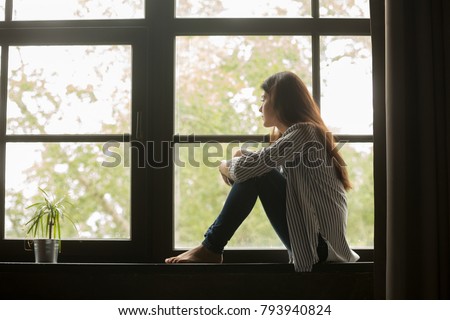 Thoughtful girl sitting on sill embracing knees looking at window, sad depressed teenager spending time alone at home, young upset pensive woman feeling lonely or frustrated thinking about problems Stock foto © 