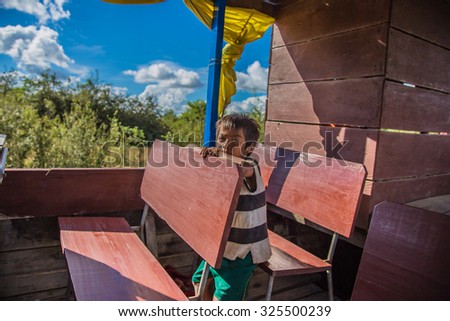 Siem Reap , Cambodia - September 10 , 2015:  boat trip in Siem Reap . A kid keep staring at me the whole boat trip in his boat .