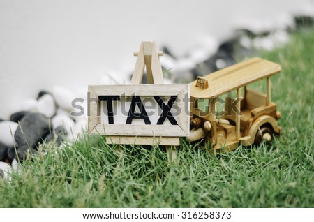 beautiful close up concept image with word TAX and wooden frame with tripod. green grass. black and white decoration rock. handcrafted iconic thailand tuktuk transport  . soft and bokeh image