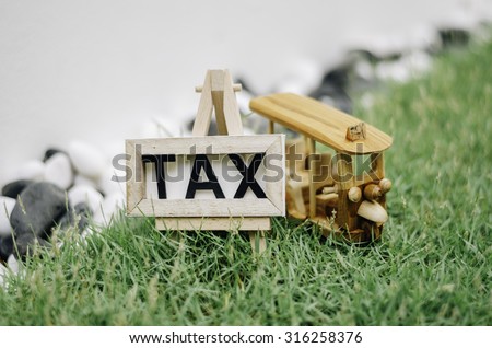 beautiful close up concept image with word TAX and wooden frame with tripod. green grass. black and white decoration rock. handcrafted iconic thailand tuktuk transport  . soft and bokeh image