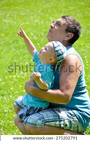 Man and child looking at the sky. The boy shows his finger to the sky.