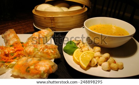 Asian dinner with rice rolls filled with shrimp, bread, scallops