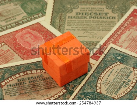 Orange small shipping box on the old, historical Polish bills, notes.