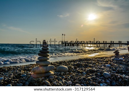 Turret pebbles at sunset with ocean on background and a quay