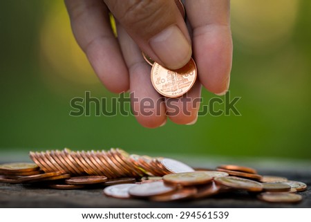 Women are collecting coins Gold for the future. Natural green background.