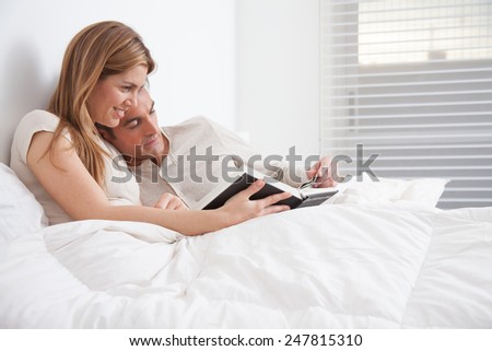 couple reading a book lying in the bed
