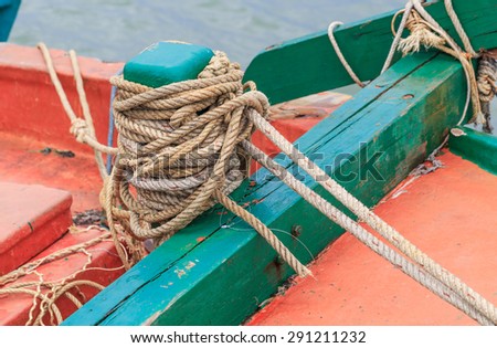 wood green Mooring Bollard with rope tied on board fishing boat
