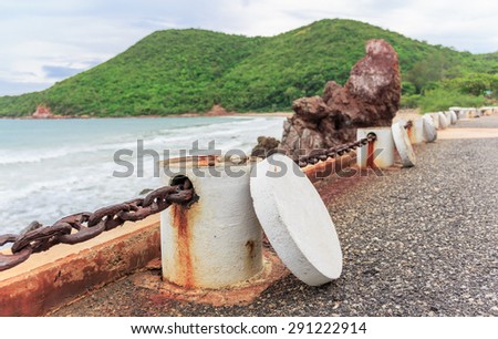 old cement pole and big black chain a long the road beside the sea nature background