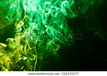 Green and yellow artistic smoke on black background texture.