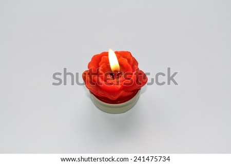 Rose-shaped ablaze candle on a white background