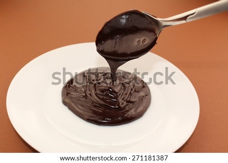 Melted semi-liquid bitter chocolate flowing onto a white plate