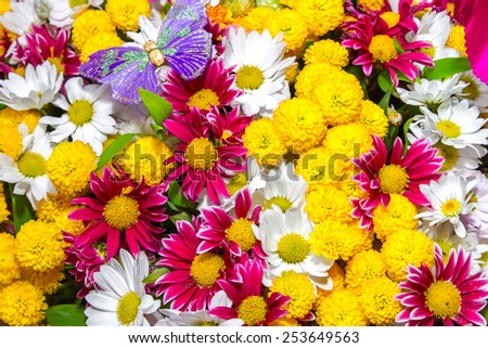 a bouquet of yellow roses and white flowers and purple butterfly