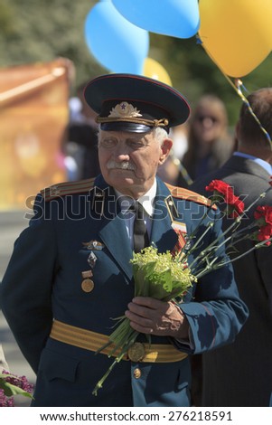 KIEV, UKRAINE - MAY 9 2014 - old man veteran dressed uniform holds flowers at a Victory celebration parade on May 9, 2014 in Kiev.