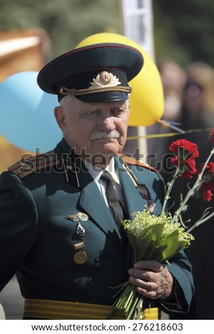 KIEV, UKRAINE - MAY 9 2014 - old officer veteran dressed uniform holds flowers at a Victrory celebration parade on May 9, 2014 in Kiev.