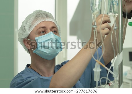 young man doctor anesthesiologist with cheerful eyes works at operating room