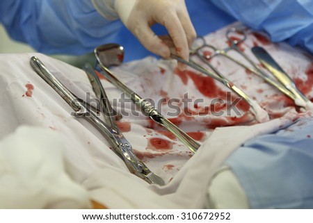 used surgical instruments on white drape with blood
