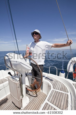 Relaxed adult man standing at the helm of a yacht in the sunshine