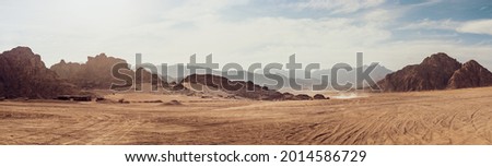 Safari and travel to Africa, extreme adventures or science expedition in a stone desert. Sahara desert at sunrise, mountain landscape with dust on skyline, hills and traces of the off-road car. Foto d'archivio © 