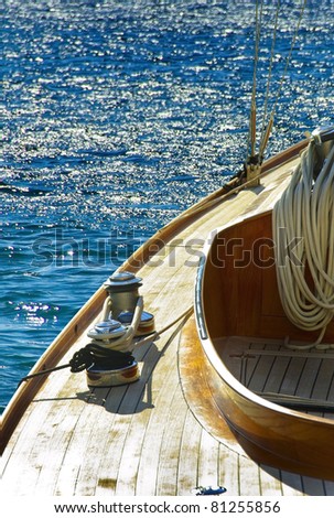 Wooden sailboat on the blue mediterranean sea. Details of a classic beautiful sailing yacht  with ropes, knots and wood plank on deck background.