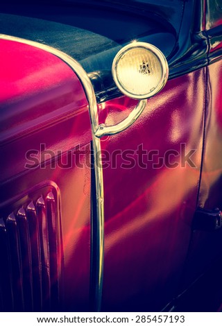 Old red car with vintage lamp - detail of retro car. Vintage auto headlight - part of antique automobile.