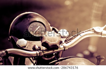 Vintage motorbike - oldtimer transport, toned old photo with sepia effect. Retro motorcycle with headlight and speedometer in monochromatic colors.