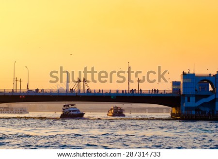 Silhouette of Galata bridge at sunset - Istanbul landmarks and seascape of the Golden Horn. Turkish passenger steamboat under the bridge, sea voyage in Turkey.
