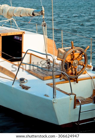 White yacht at sea with steering wheel in front view. Skipper\'s wheel and sail on an old ship. Sea voyage on the yacht, captains wheel on the deck of the old sail vessel.
