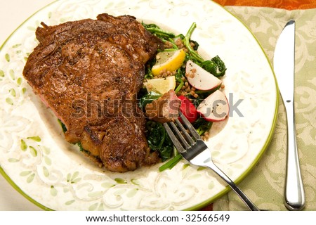 Cut rare ribeye steak with wilted watercress salad