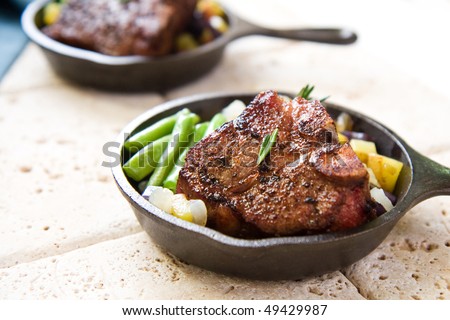 Lamb served with green beans and diced blue and gold potatoes in miniature cast iron skillet