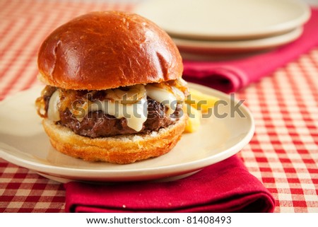 Rare cheeseburger with caramelized onions and melted swiss cheese on large roll