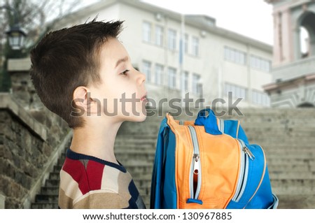 Boy with school bag in front of the school